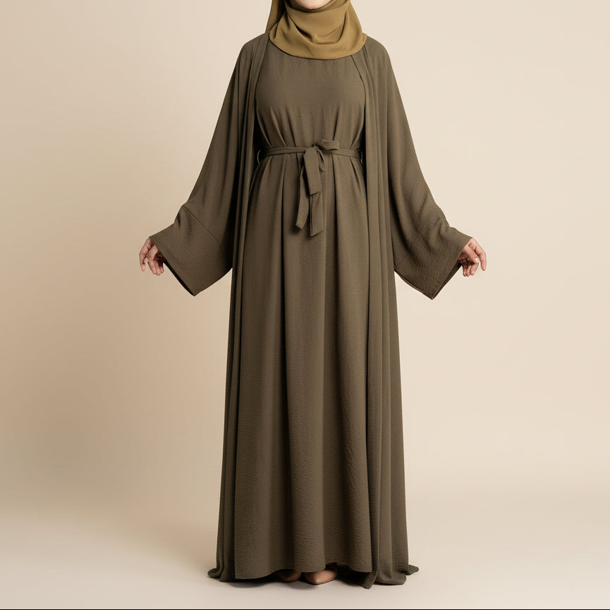 Woman wearing a long olive green dress with a matching hijab on a white background