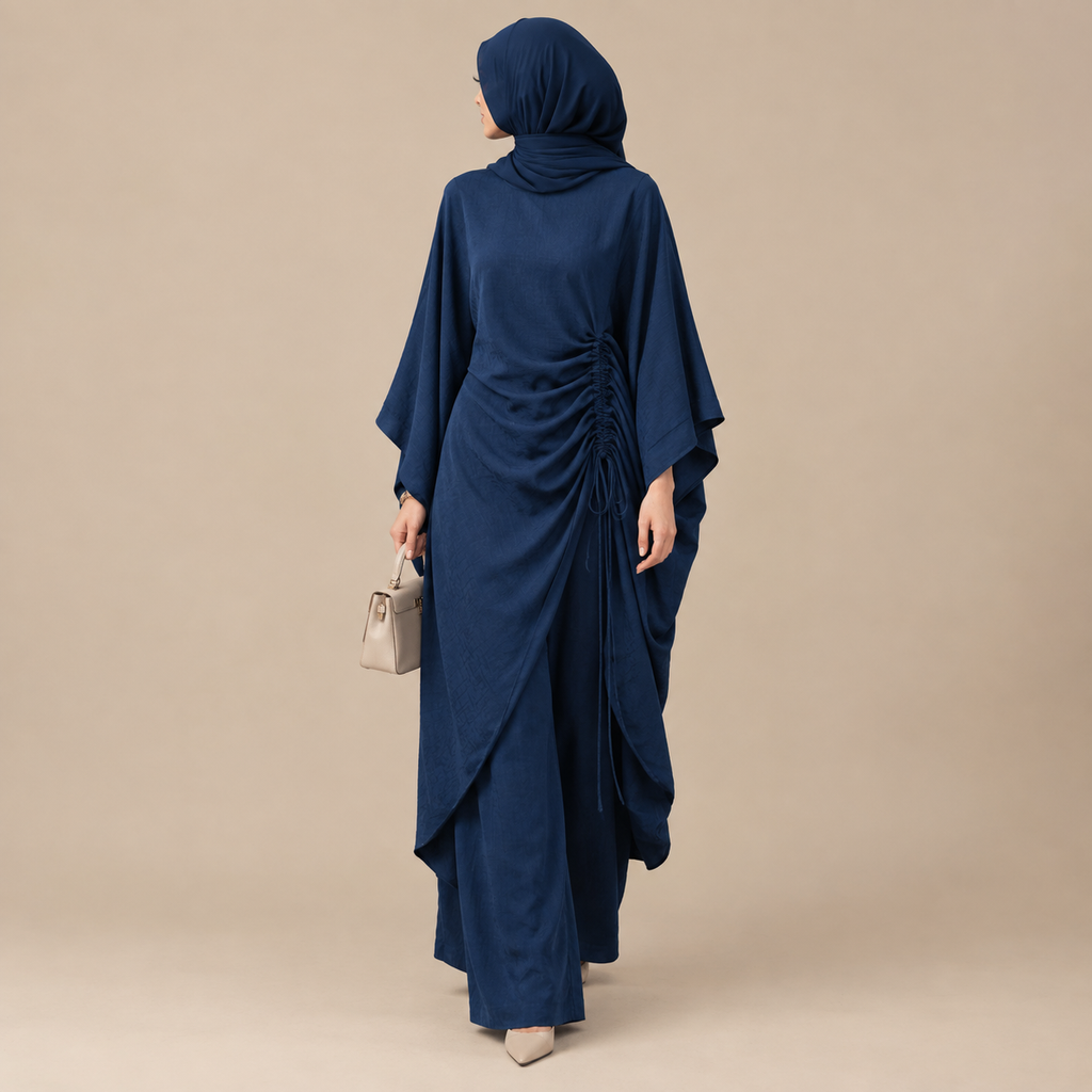 A woman wearing a navy blue modest dress with a matching hijab, shown from the back against a plain beige studio background. She is holding a small light beige handbag.
