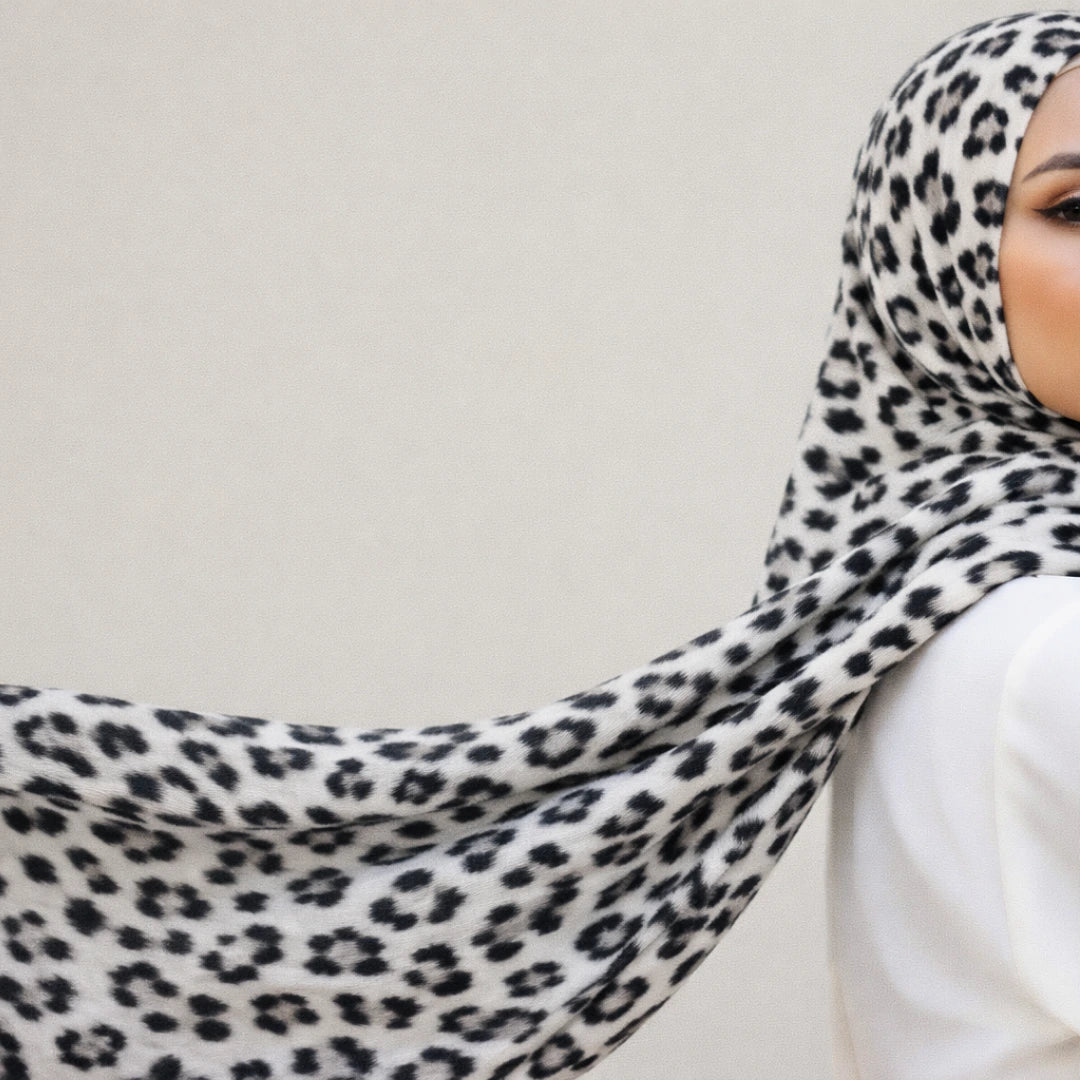 Person wearing a leopard print hijab against a plain background