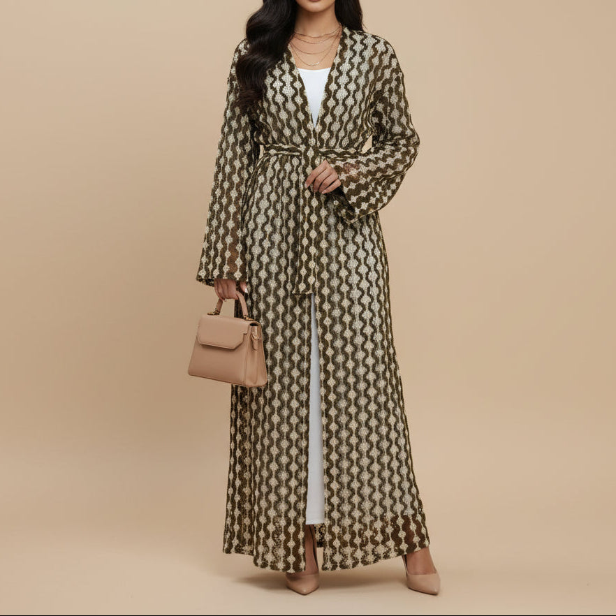 A long-sleeved maxi robe with a beige and brown wavy geometric pattern, worn by a model over a white top and white trousers, photographed against a seamless white studio background.