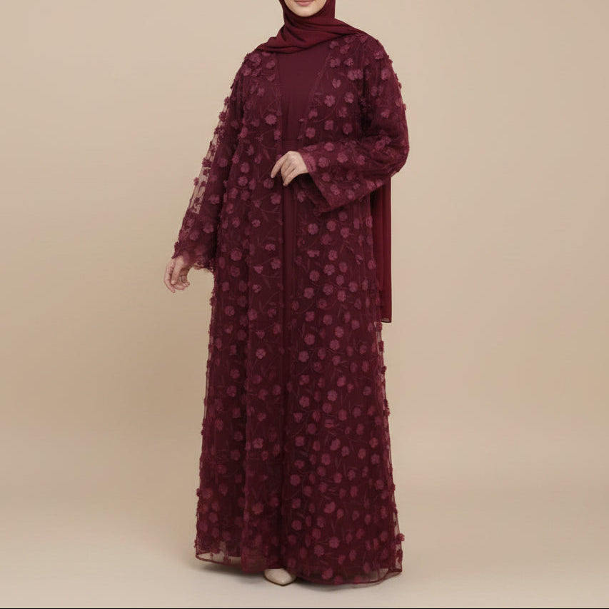 Woman wearing a burgundy floral dress with a rack of matching scarves in the background.