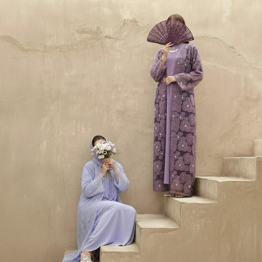 Two women in matching purple abaya dresses on a beige staircase. wearing luxury abaya Ramadan collection US, UK, Canada