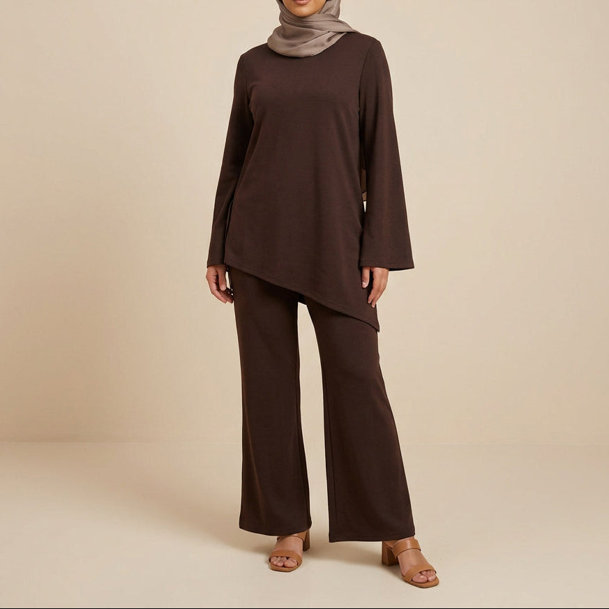 A dark brown two-piece lounge set displayed on a mannequin, featuring a long-sleeve asymmetrical top and matching wide-leg pants, set against a white paneled wall.