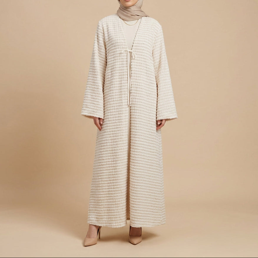A long-sleeved, floor-length cream and beige textured knit robe with a drawstring V-neck, displayed on a mannequin against a white paneled wall.